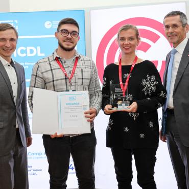 Ronald Bieber und Wilfried Seyruck mit zwei Lehrer*innen einer ausgezeichneten ICDL Schule bei der Urkunden und Pokal-Übergabe, im Hintergrund ICDL und OCG Logos